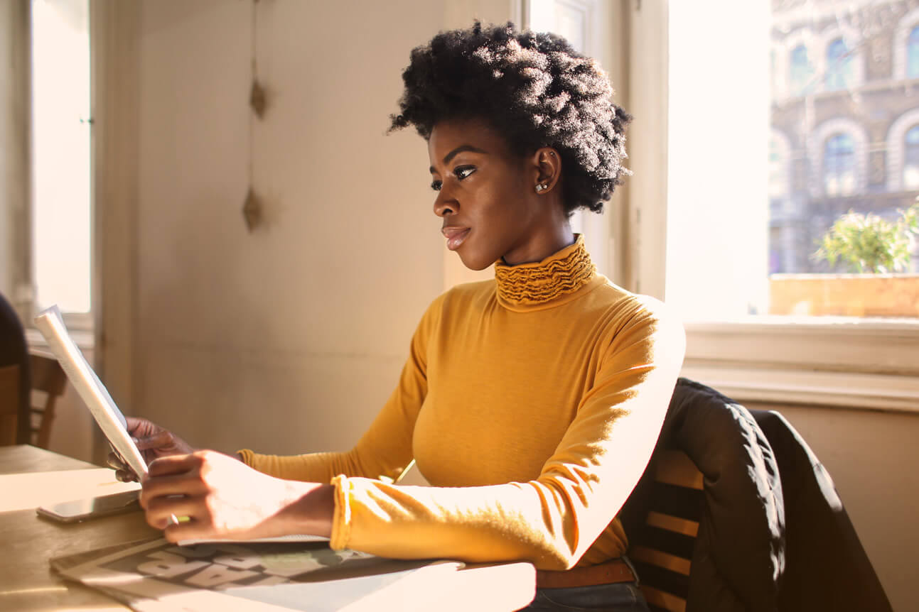 beautiful black woman reading a newspaper as part of her good habits