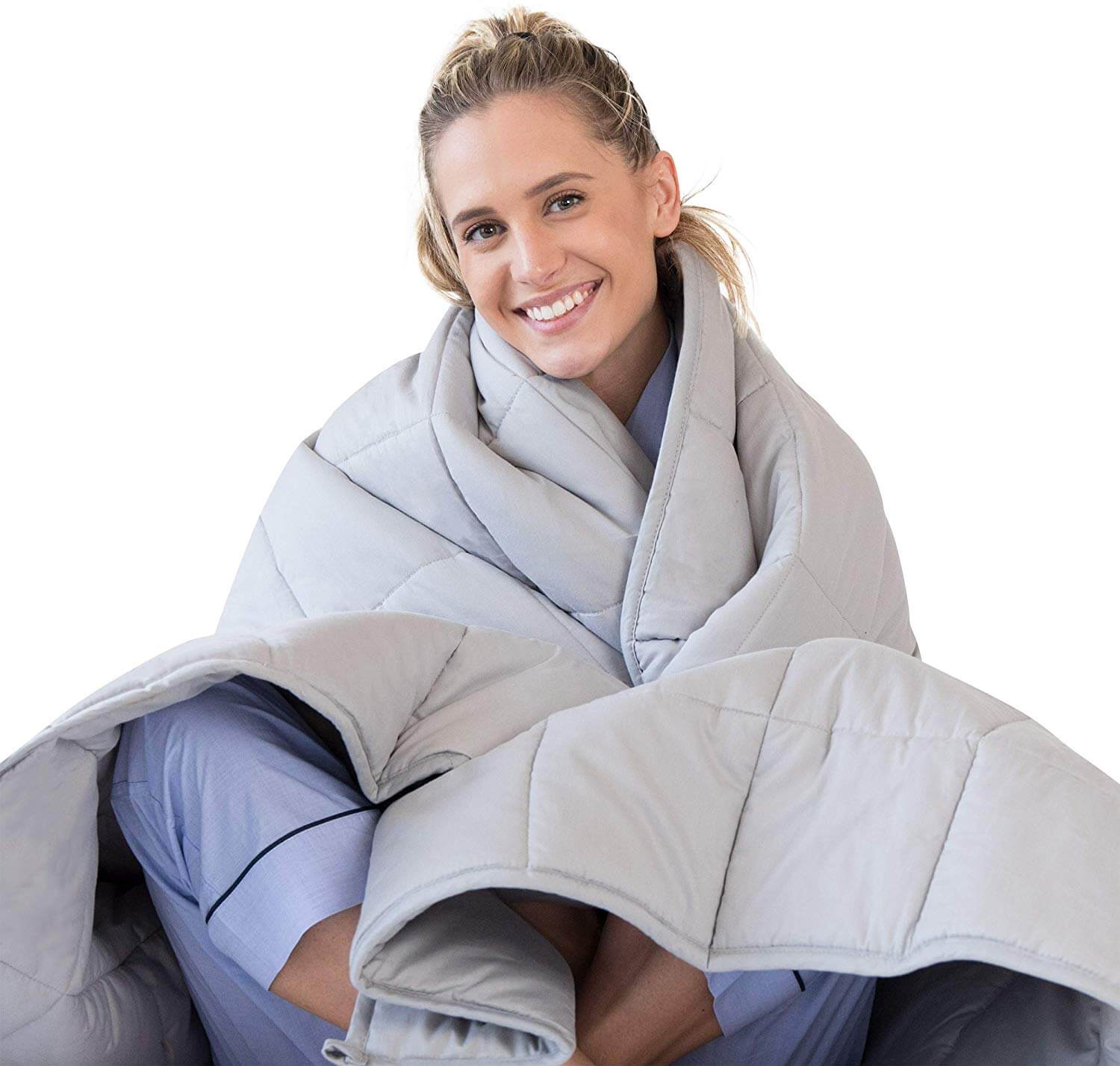 A young blond woman sits under weighted blanket
