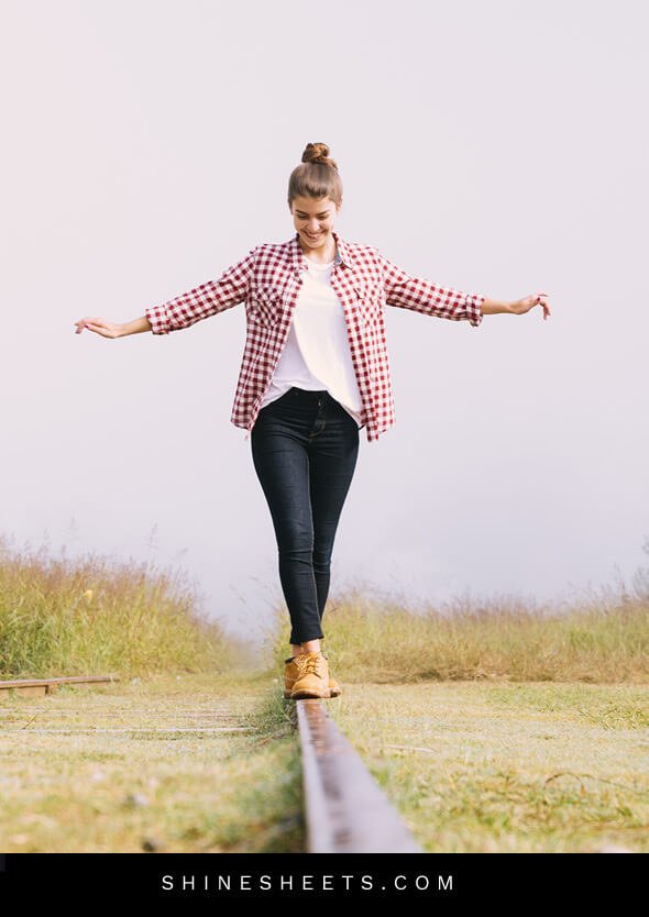 happy woman walking on railtrack as a concept of living happier with life balance
