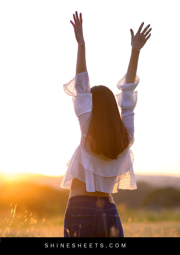 woman with her hands in the air as a symbol of living happier