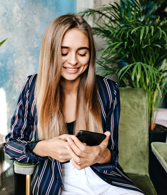 girl smiles while writing a text message and trying to decipher how to know if someone has a crush on you