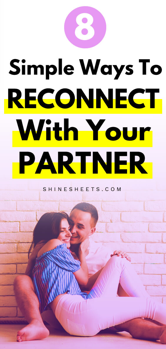 Happy couple sitting near white brick wall and hugging each other while smiling