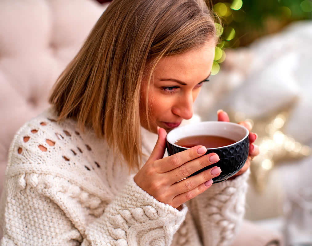 Woman drinking tea and taking self care as part of her success habits