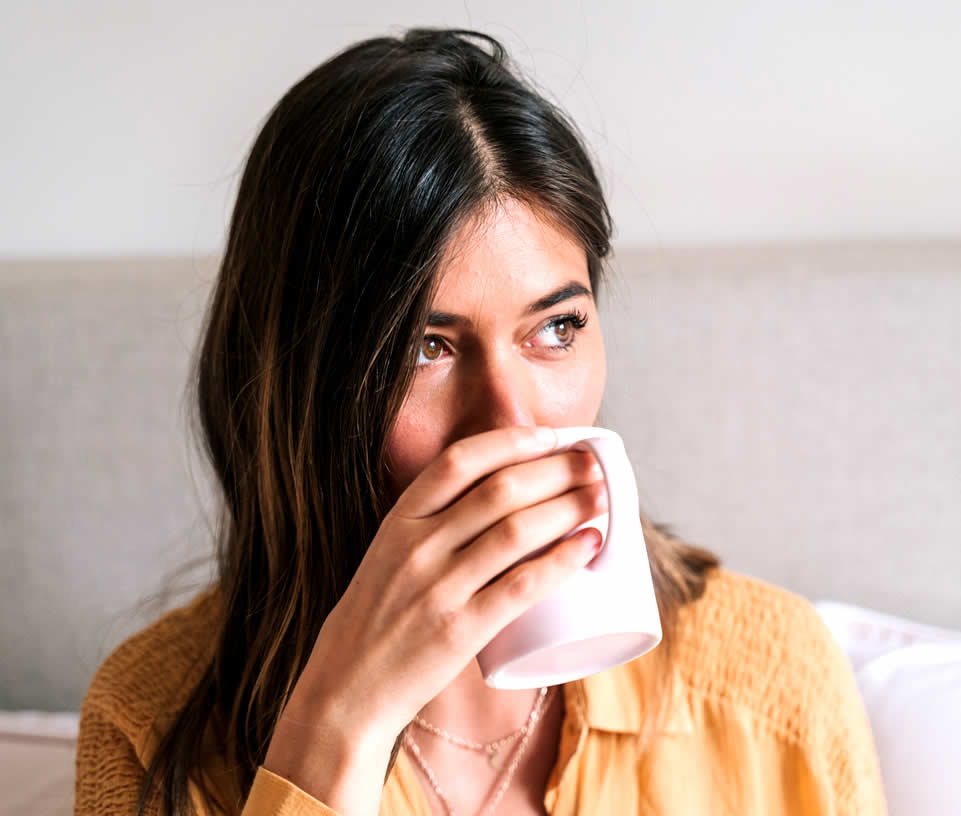Woman is having health anxiety and is drinking tea from a pink cup