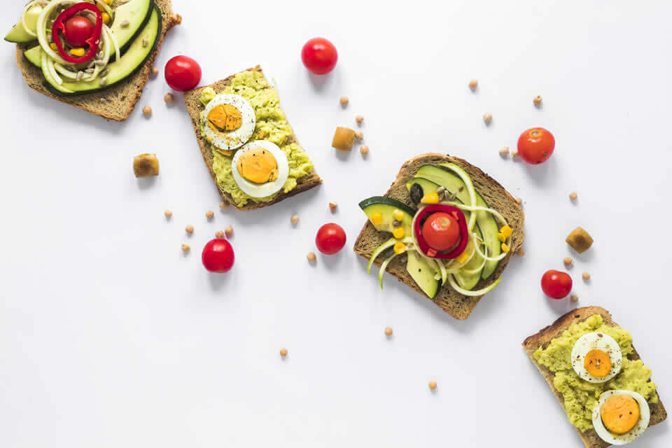 Healthy breakfast example of sandwiches with avocado, eggs and vegetables