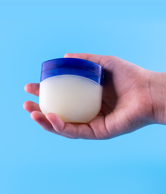 person holding vaseline petroleum jelly jar in hand