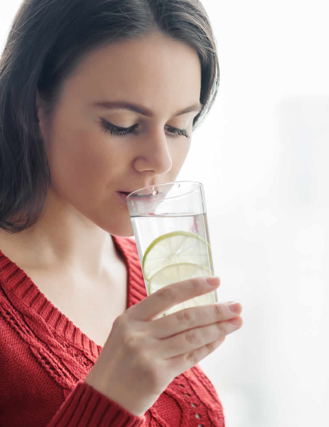 O woman drinking glass of lemon water on her wellness day