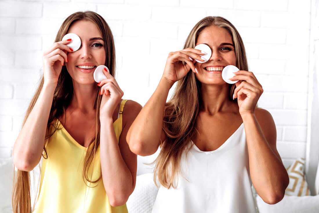 Two beautiful women in a room using green tea pads to grow eyelashes