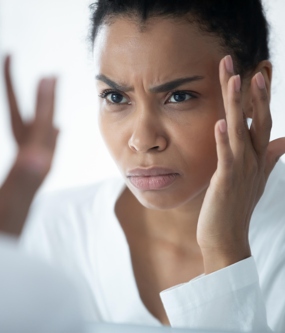 frowning woman inspecting her skin