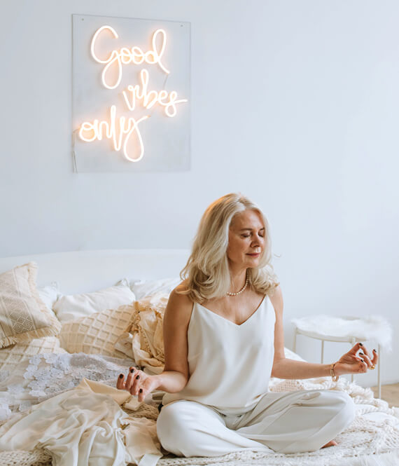 woman meditating under good vibes only sign