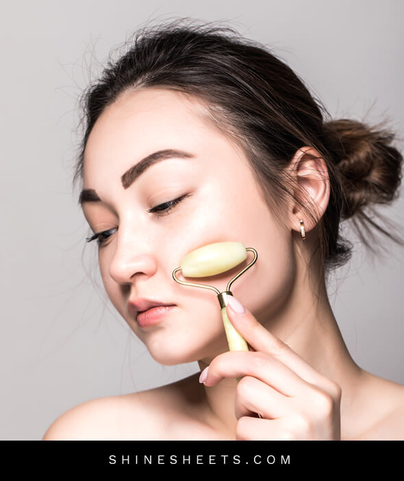 woman using jade roller to massage her face after reading beauty tips for face