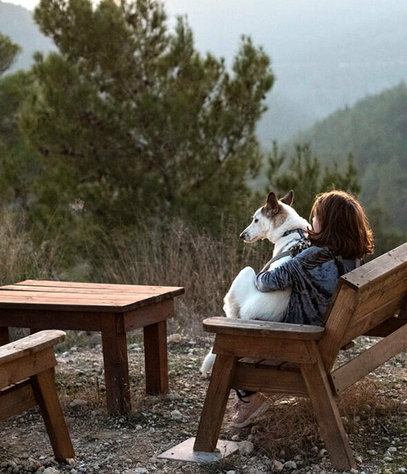 woman sitting with her dog on a mountain to find inner happiness