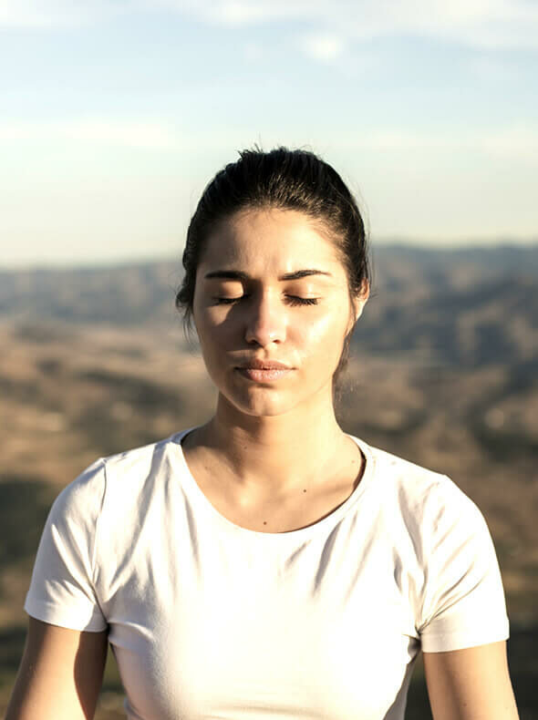 woman meditating on a mountain to find inner happiness