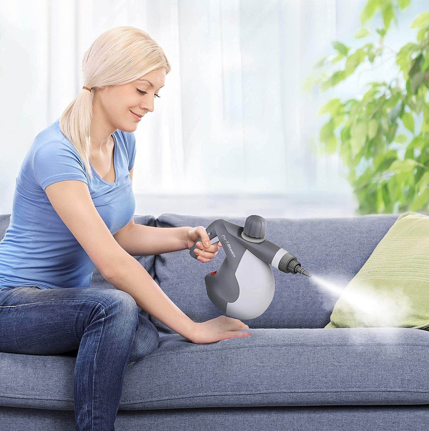 Young blonde woman using steam cleaner to clean sofa