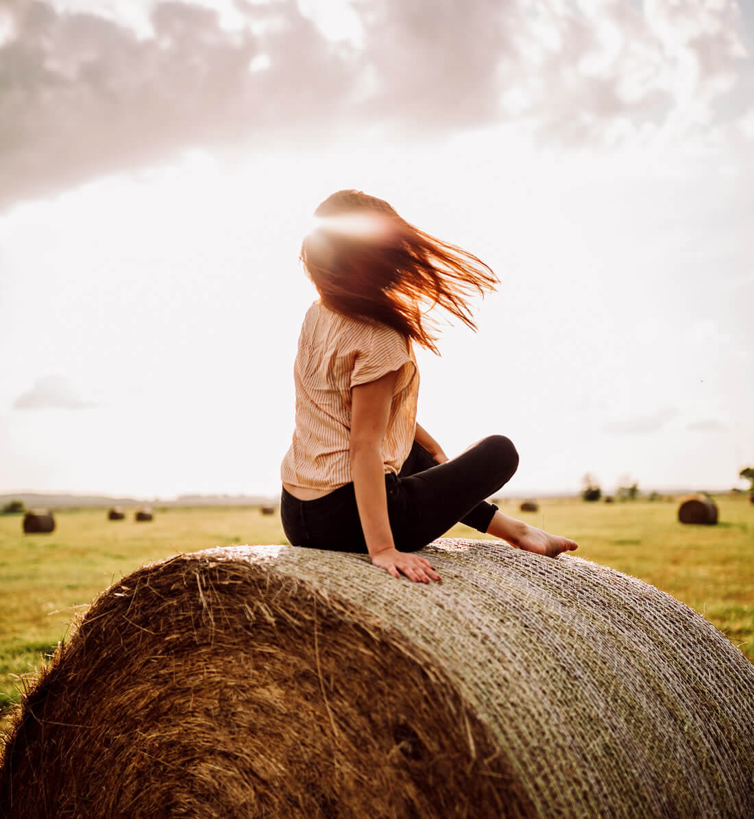 Woman sitting in the nature on hay stack to practice self love