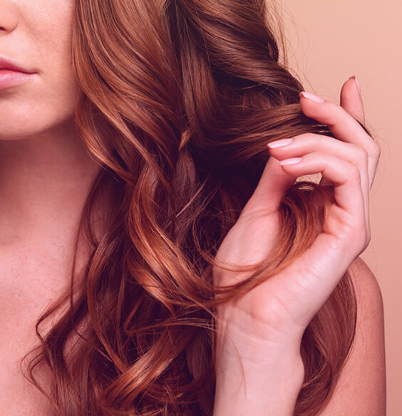 young woman touching her red hair to stop hair loss