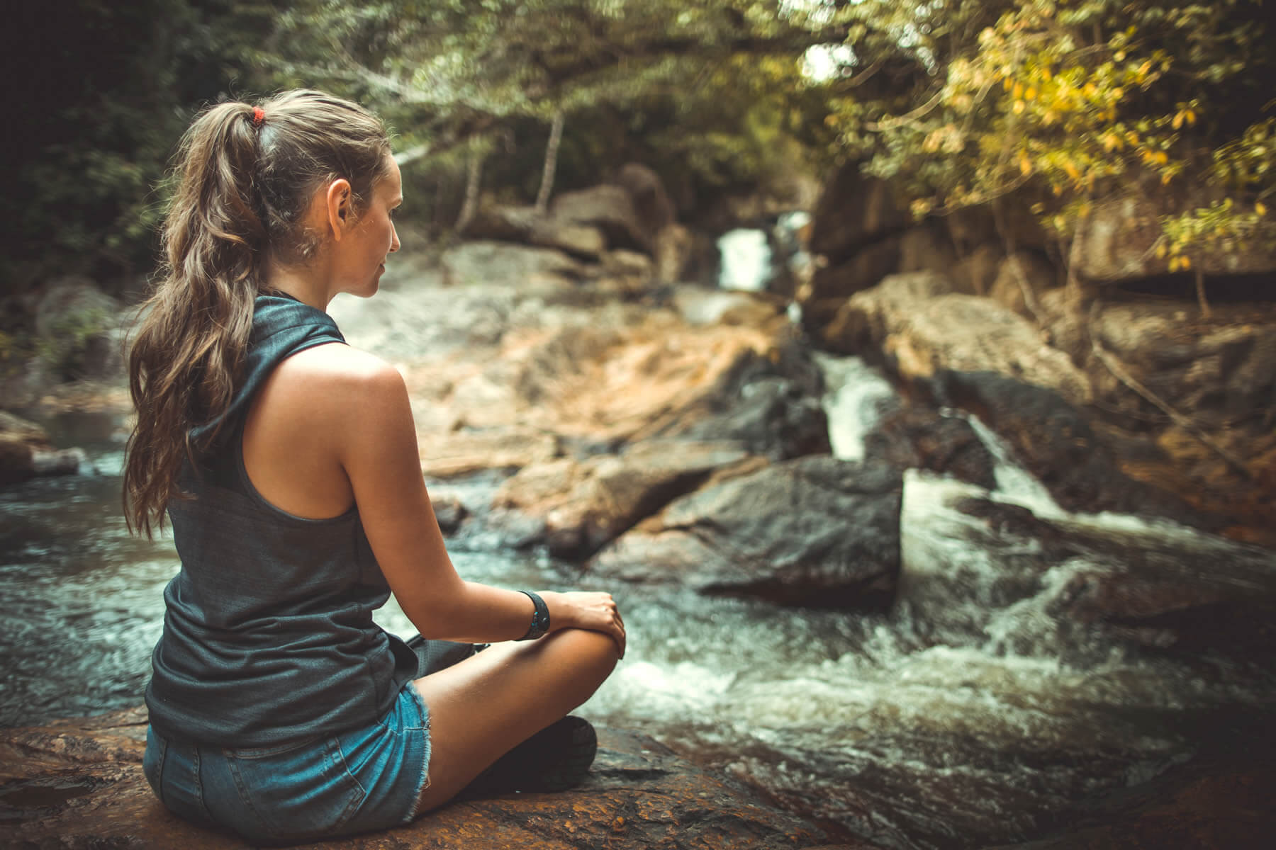 Woman sitting in near a stream to overcome anxiety