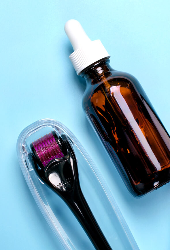 derma roller and serum bottle on blue surface