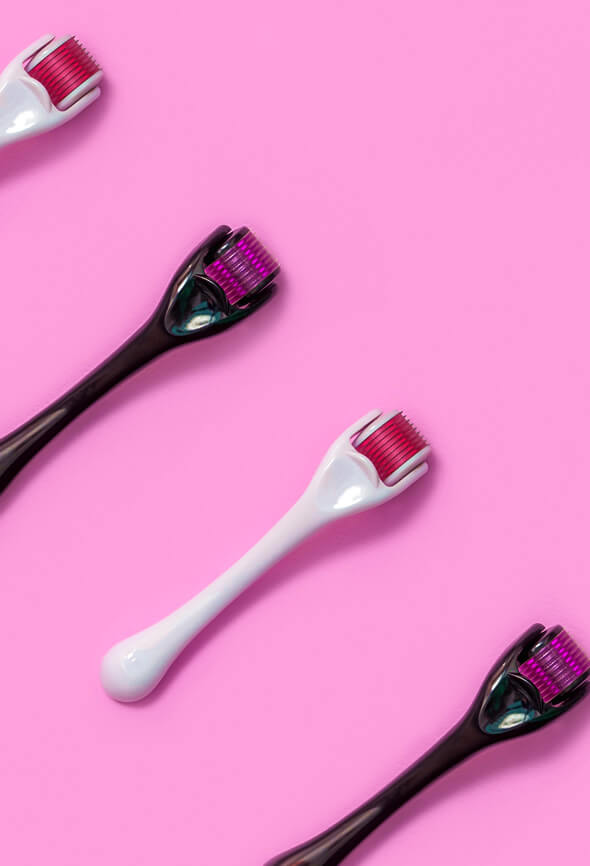 derma roller devices in various sizes on pink surface