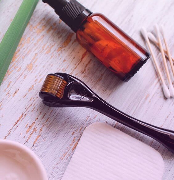 derma roller, serum and cotton buds on the table