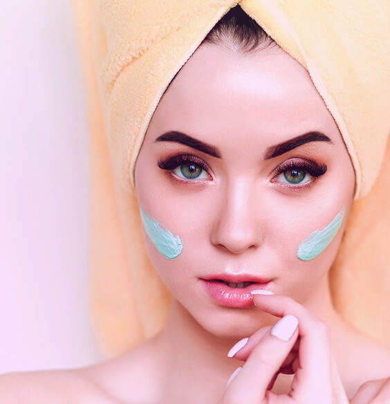 young woman using face pack on her skin