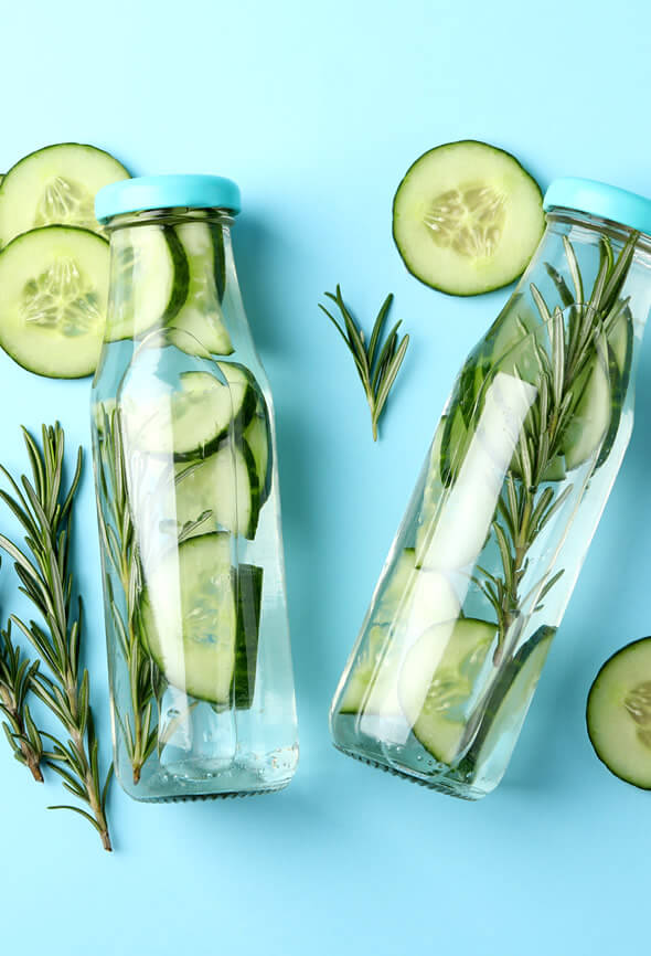 Cucumber infused water bottles with rosemary as one of the wellness tips