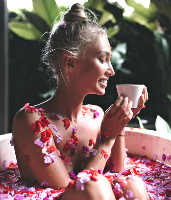 joyful happy lady having a bath with flower petals