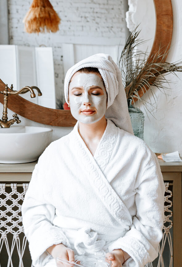 woman in the bathroom sitting with a face pack on