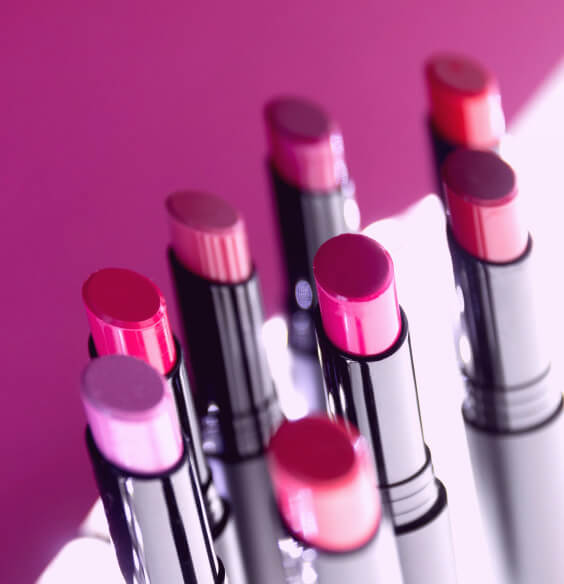 various lipstick shades on a pink background