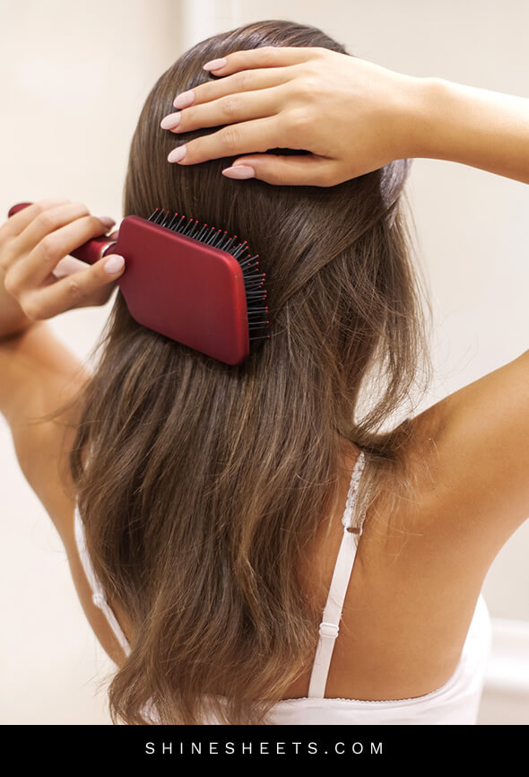 woman brushing healthy hair after doing beauty habits for hair improvement