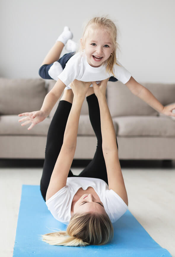 woman playing with her child on yoga mat as part of her active lifestyle
