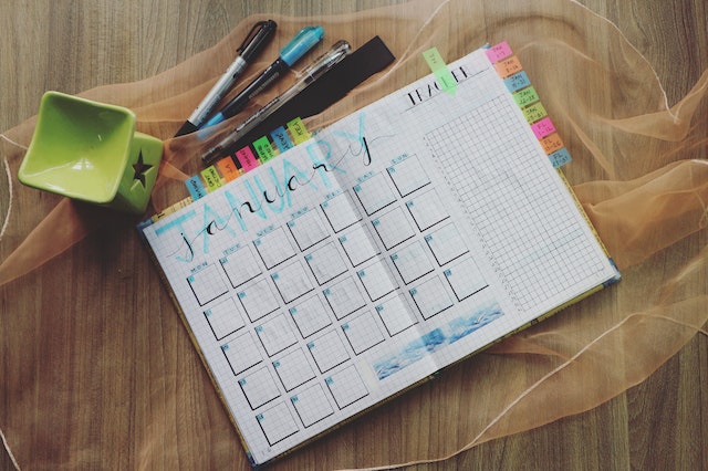 a monthly planner on the table, with pens next to it