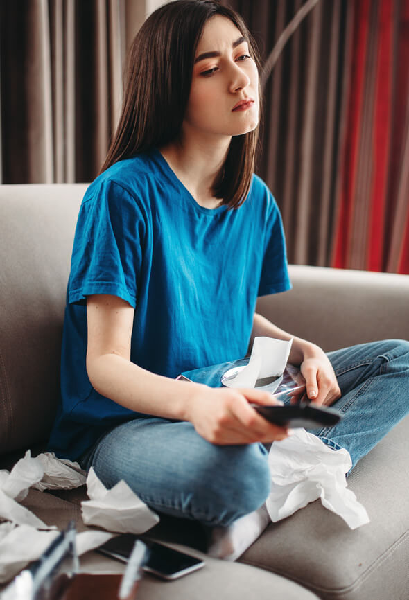 woman crying on the couch near tv because she is in impossible love