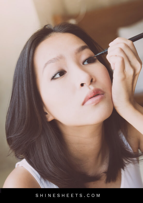 young asian woman applying makeup on her hooded eyes