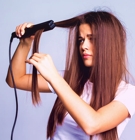woman trying to straighten her frizzy hair with a flat iron