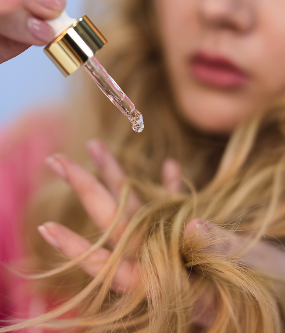 blonde girl applying hair serum to hair that feels damaged