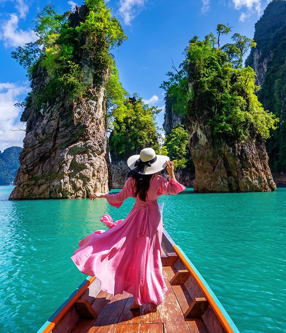 woman with a hat and pink dress near water body
