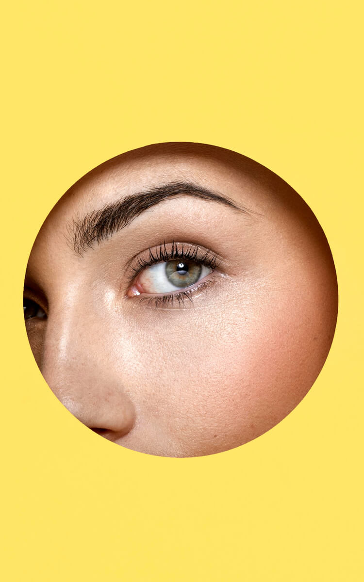 woman eye through a hole in yellow paper