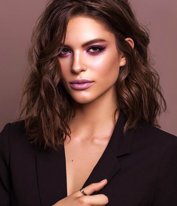 stylish brunette woman with wavy hair and black tuxedo jacket