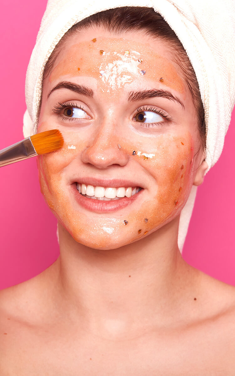 woman applying a tomato based facial mask