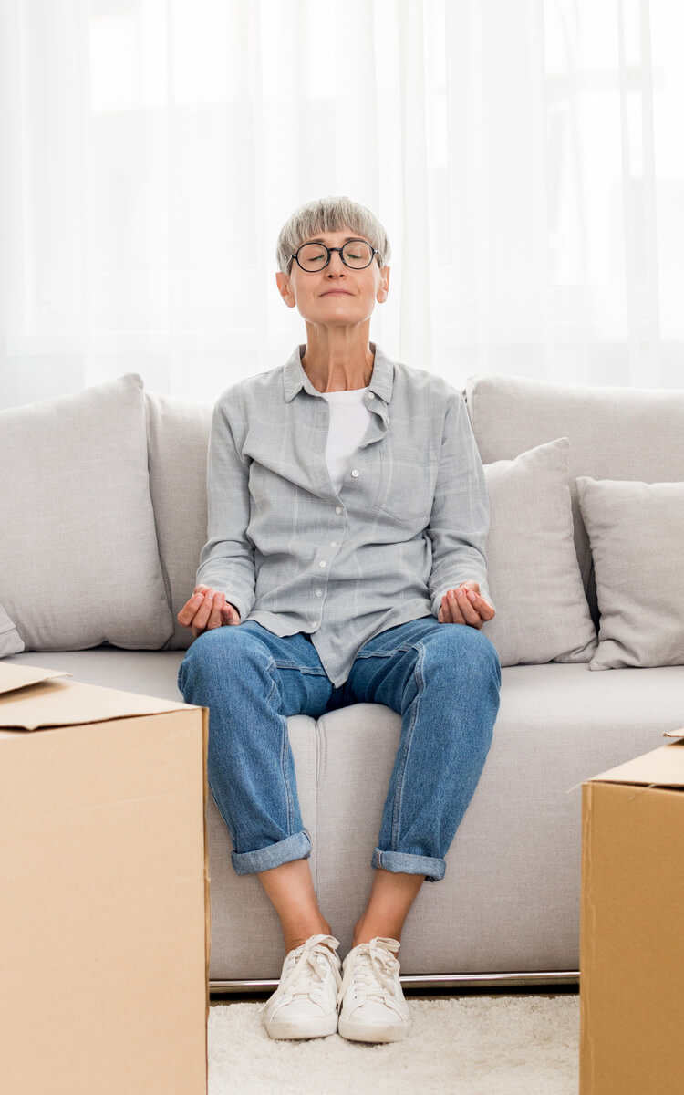 pretty mature woman meditating between boxes