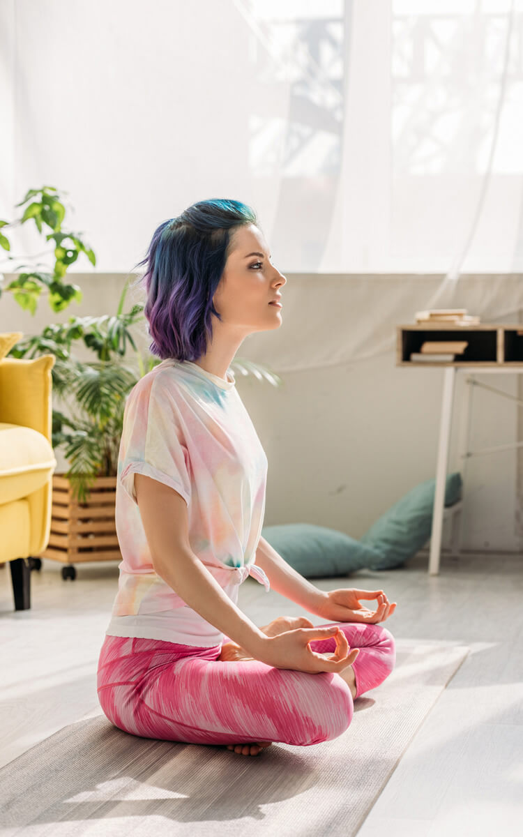 young woman with colorful hair meditating on the floor