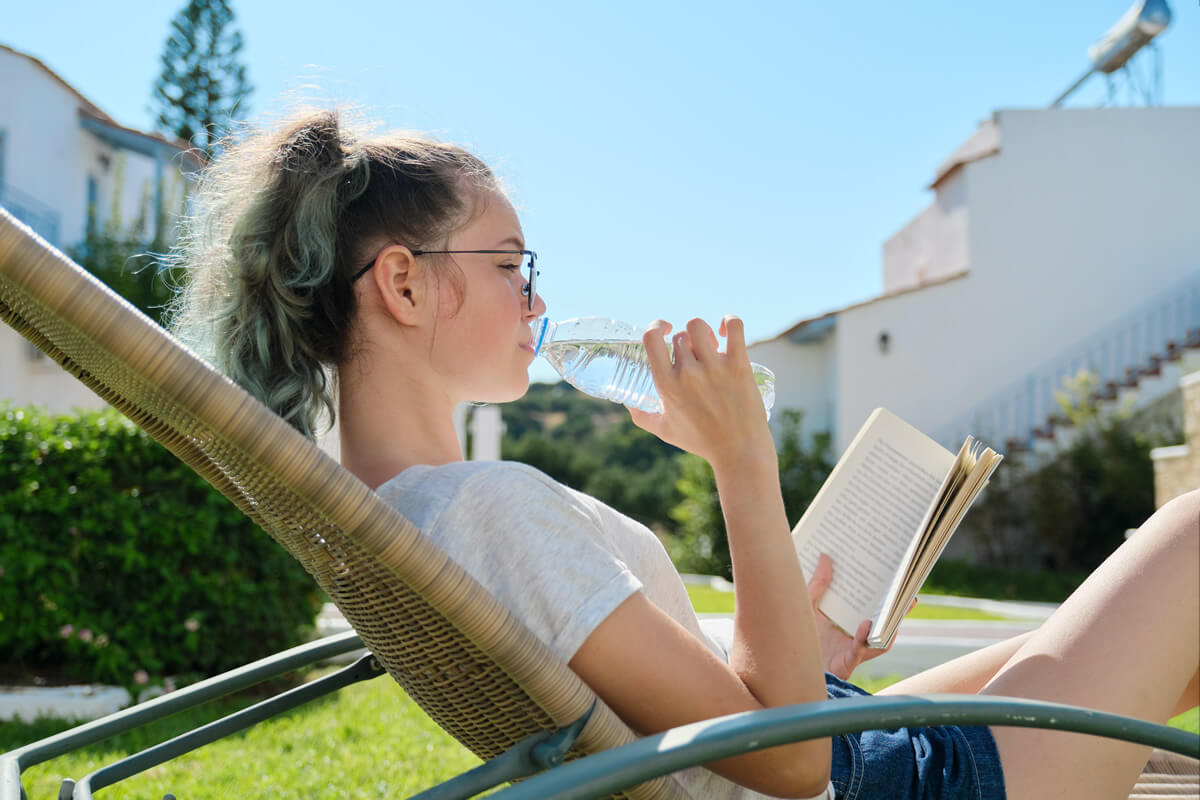college student girl reading outside and drinking water