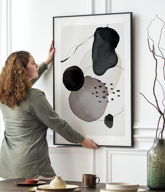 woman hanging a big piece of wall art in a living room