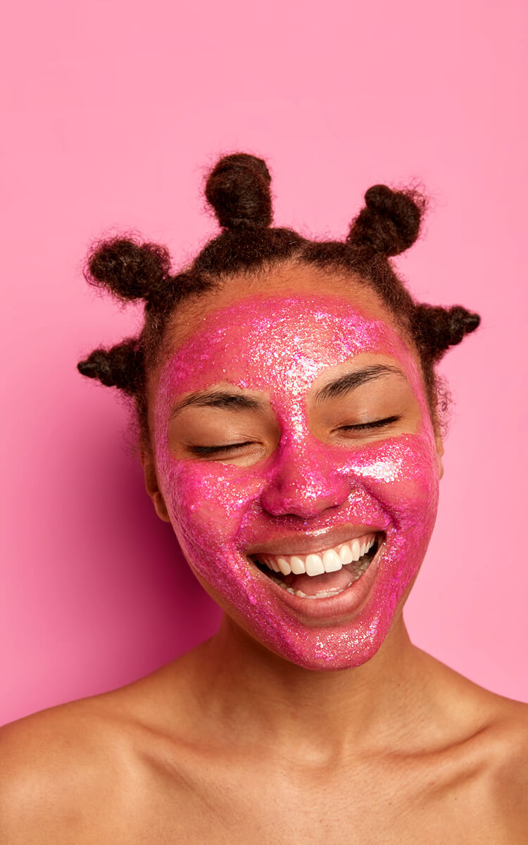 woman smiling with a glittery face mask