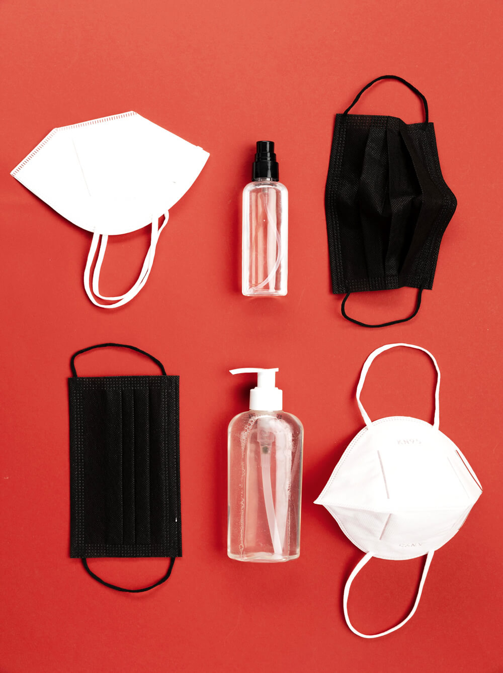 face masks, respirators and hand sanitizer on a red table