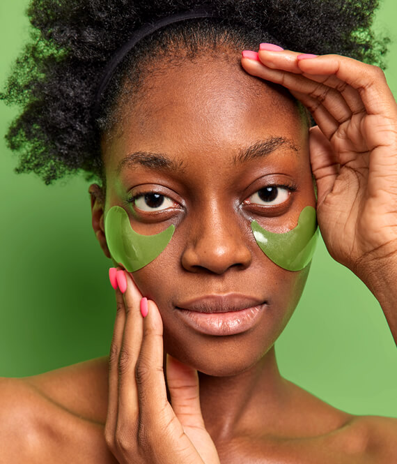 gorgeous black woman using hydrogel eye patches on her face