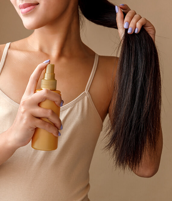 woman using anti hair loss spray on her hair
