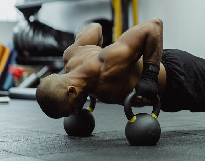 man doing kettle bell push ups in the gym