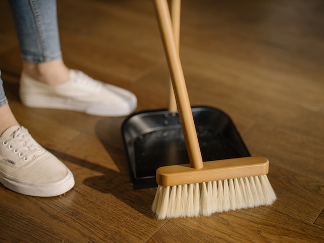 a person sweeping the floor with a wooden brush